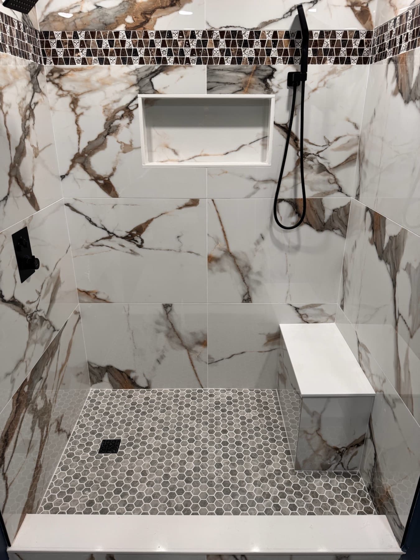 Brown and white tiled shower with a built in white bench in Gulf Breeze, FL