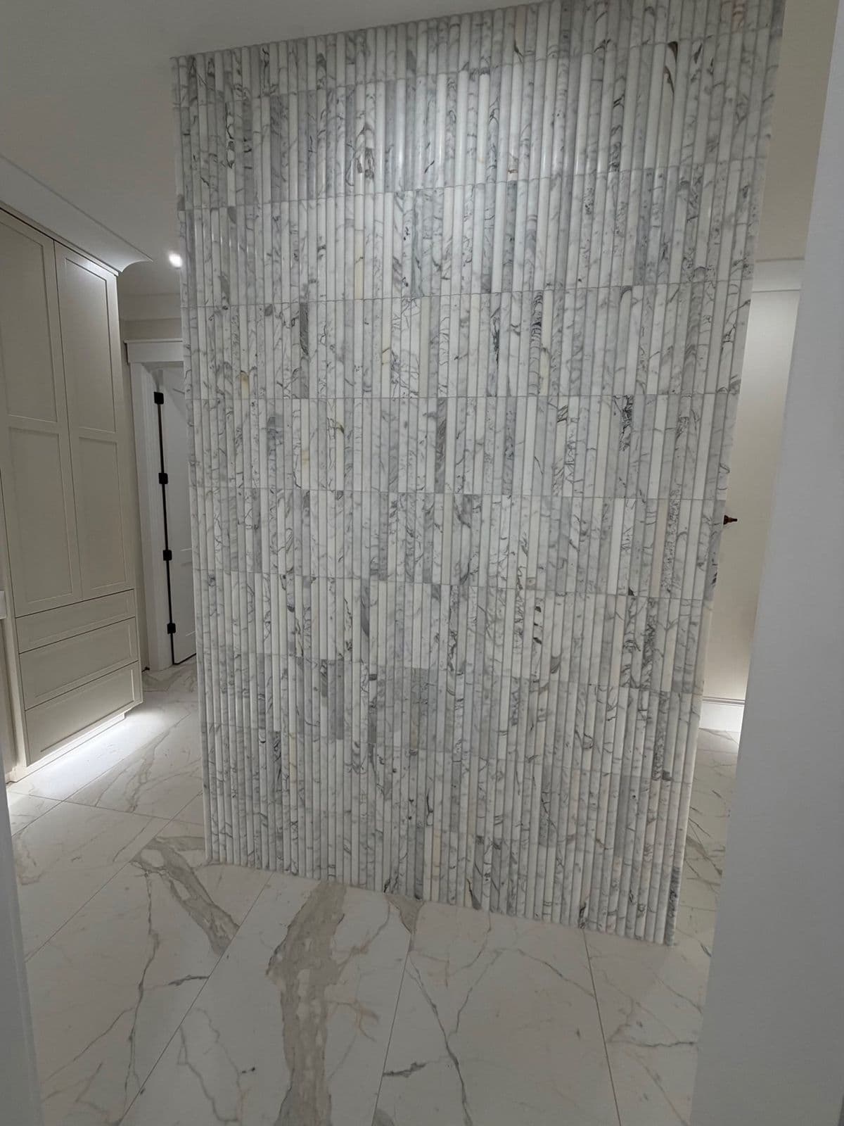 Tile feature wall installation in Pensacola, FL: fluted stone accent wall with marble look porcelain floor in Pensacola, FL