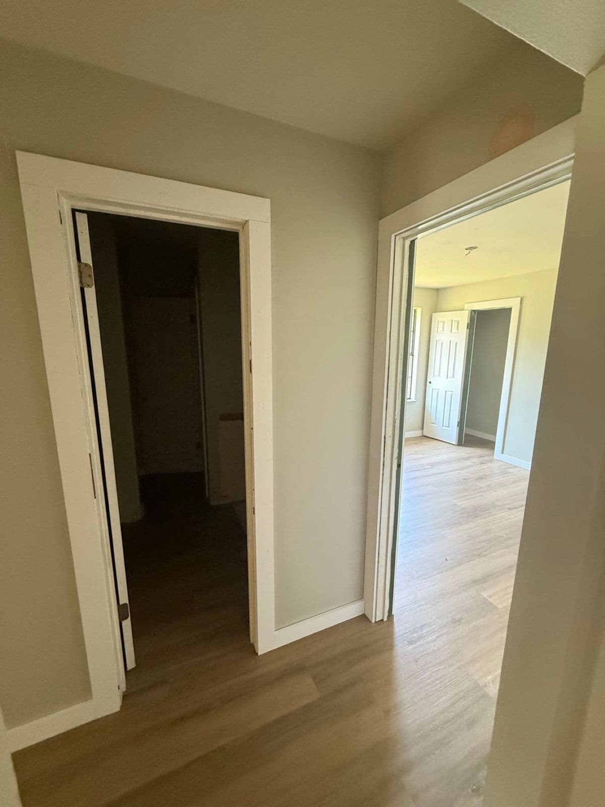 Luxury vinyl plank installation in Pensacola, FL: light oak LVP running through a hallway and bedrooms by Custom Tile & Design