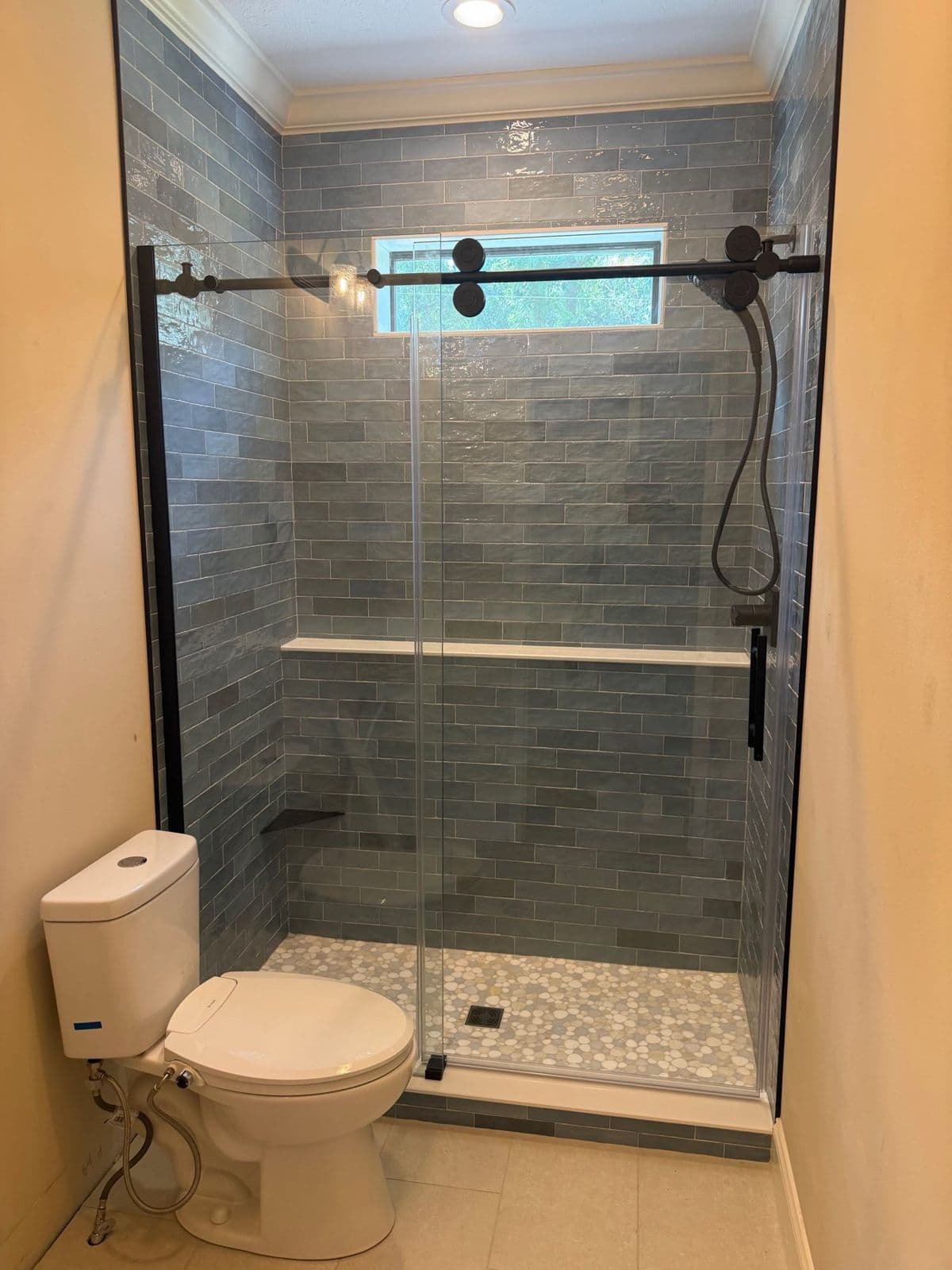 Tub to shower conversion in Pensacola, FL: sage green subway tile shower with sliding glass door and pebble floor by Custom Tile & Design