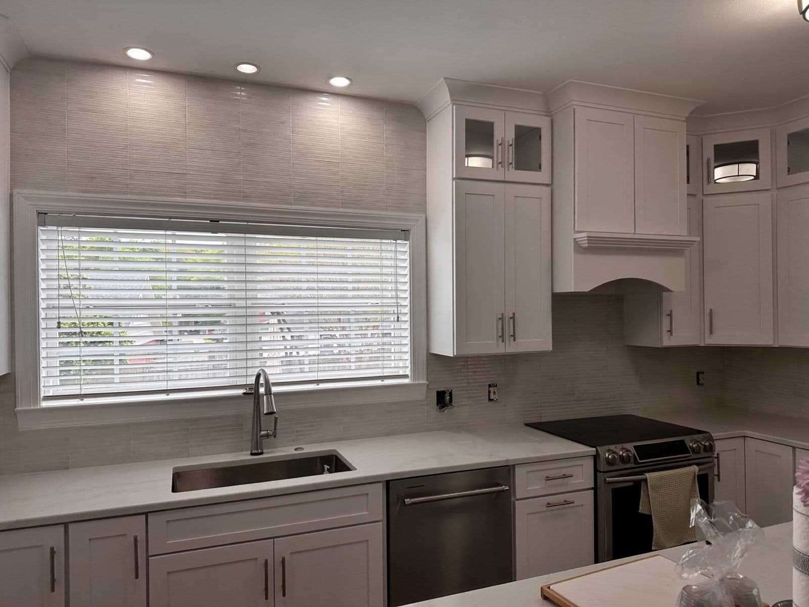 Kitchen backsplash installation in Pensacola, FL: grey subway tile backsplash with white cabinets and quartz counters by Custom Tile & Design
