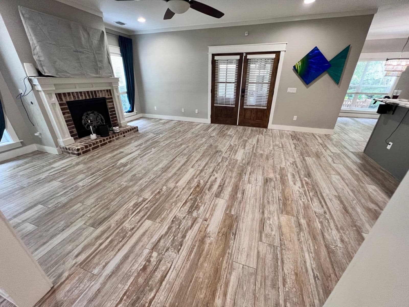 Wood look tile installation in Pensacola, FL: whitewashed plank tile in a living room, the tile side of the tile vs. LVP choice