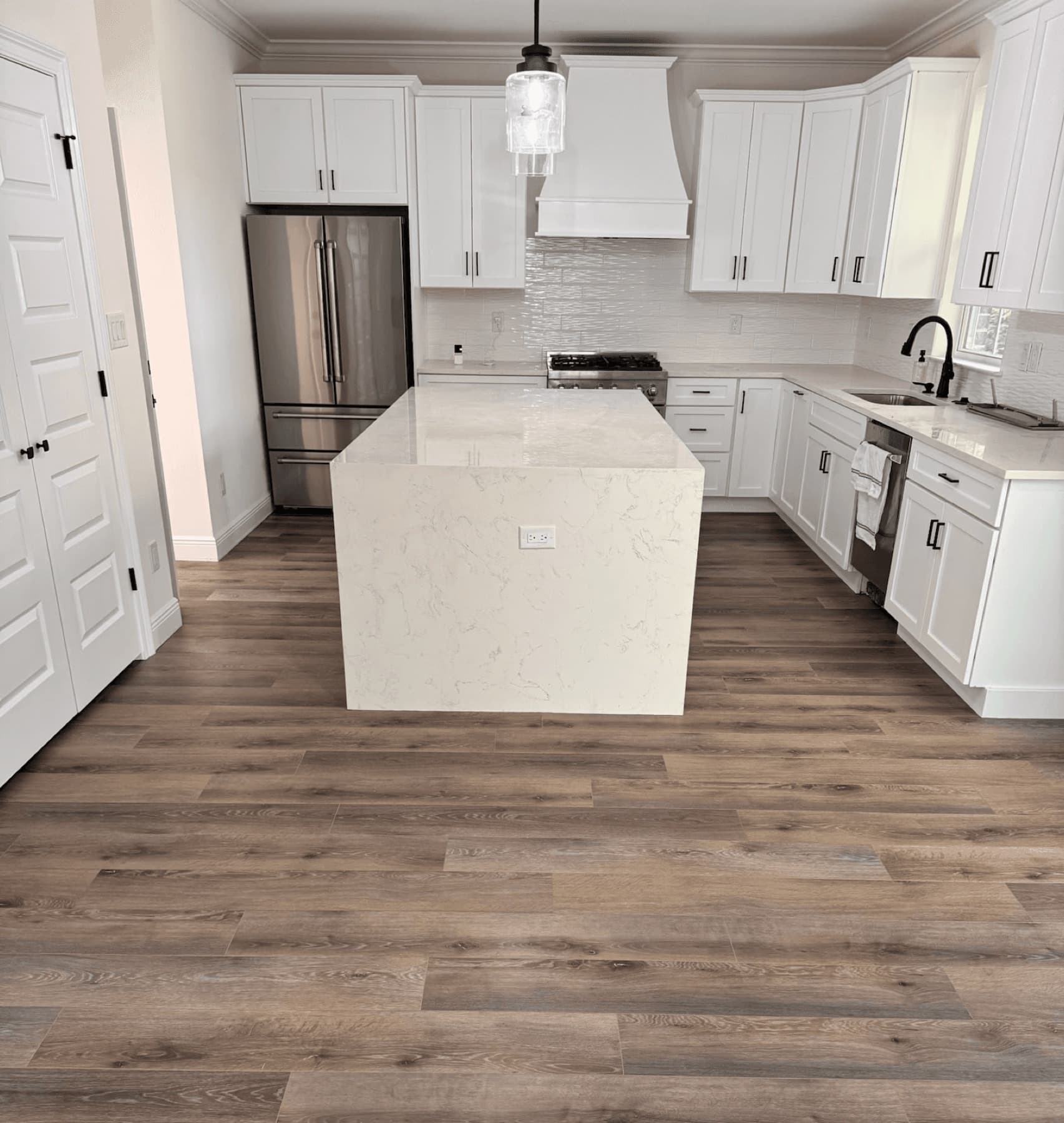 Remodeled kitchen with white cabinets, white island, and light tan floors in Pensacola, FL