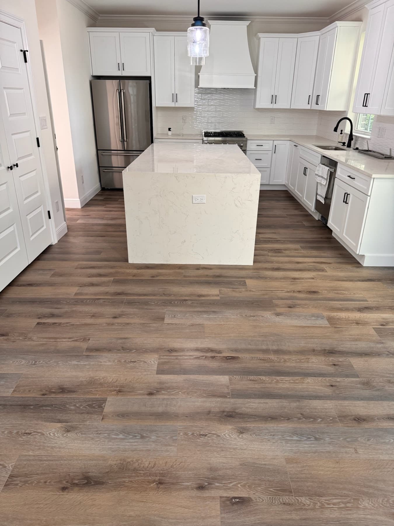 Light brown luxury vinyl plank floor in a white kitchen in Pace, FL