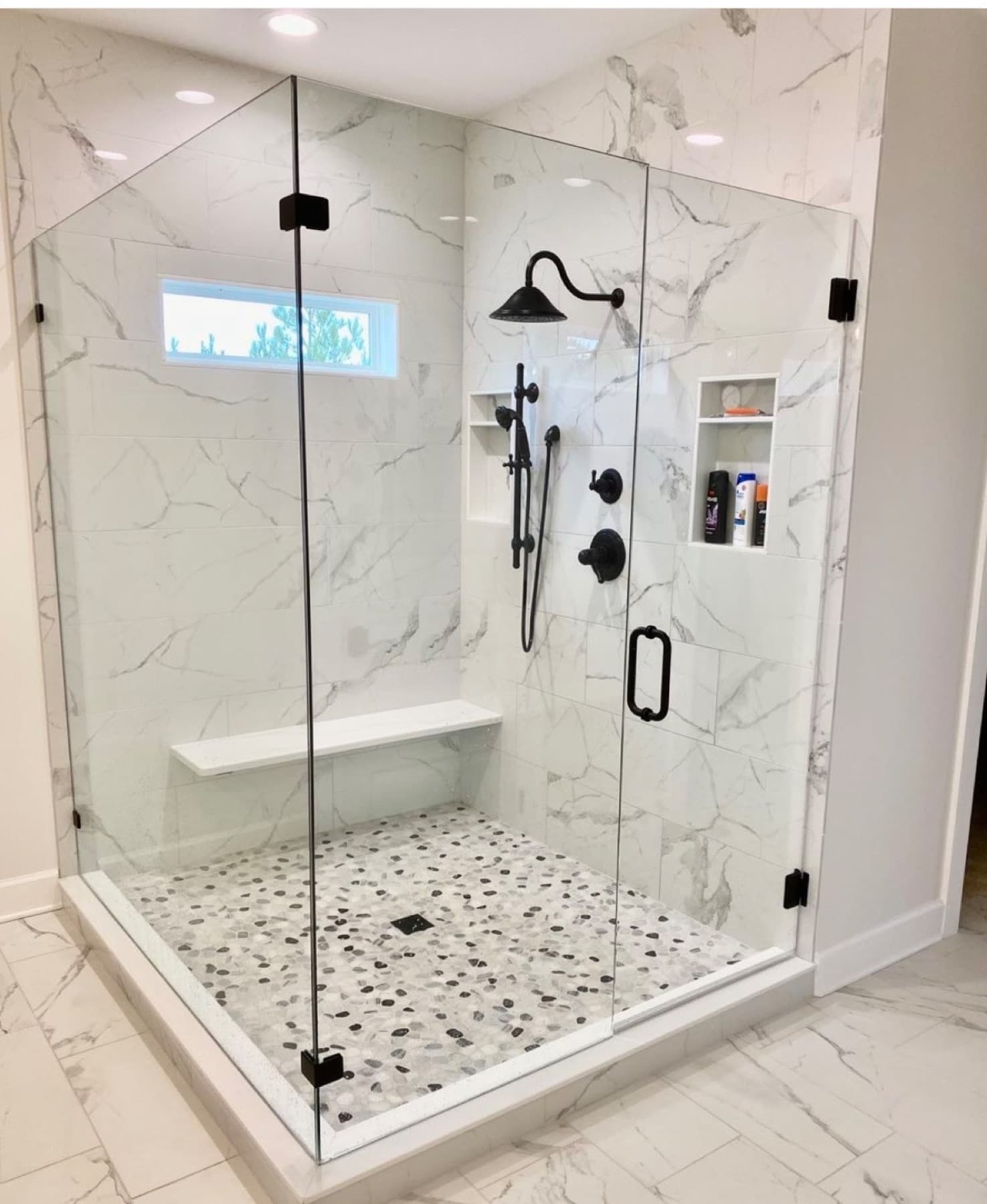 White and grey marble tile shower with glass sides and black fixtures in Pensacola, FL