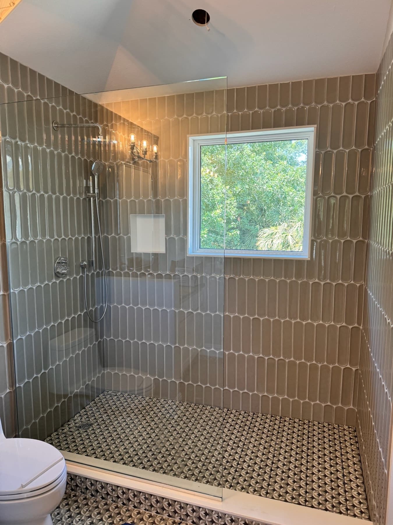 Shower with vertical stacked taupe tile and a window in Gulf Breeze, FL